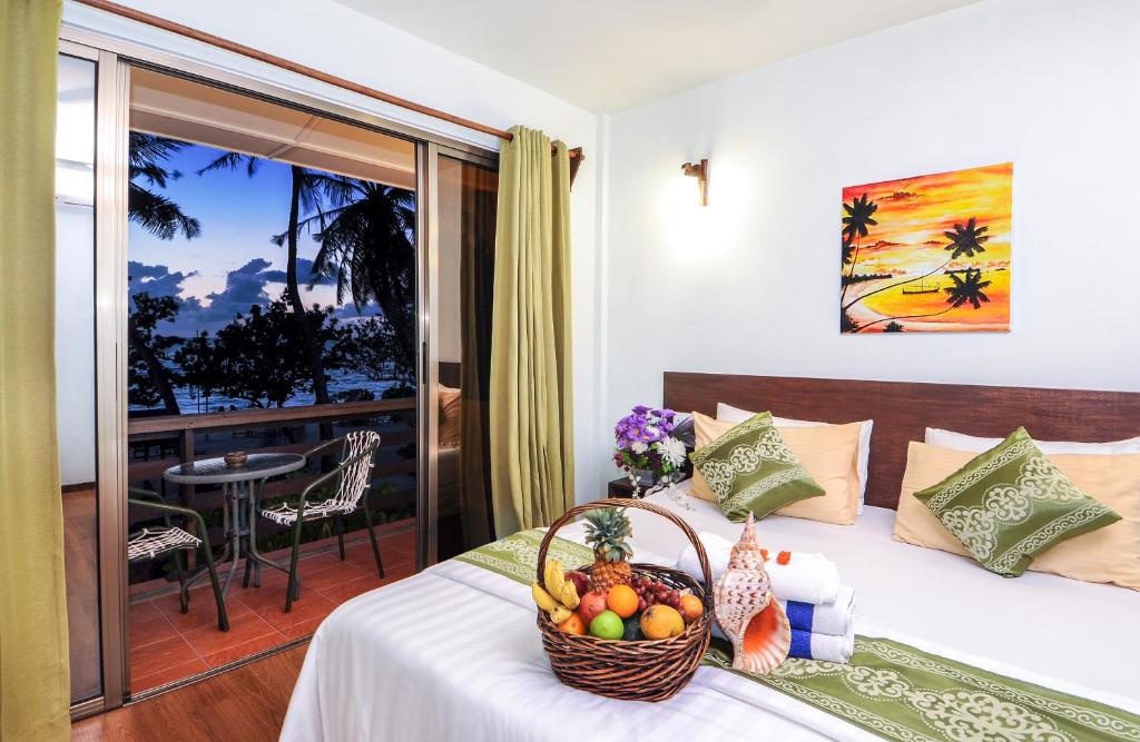 a room with a bed with a basket of fruit on it at Salt Beach Hotel in Maafushi