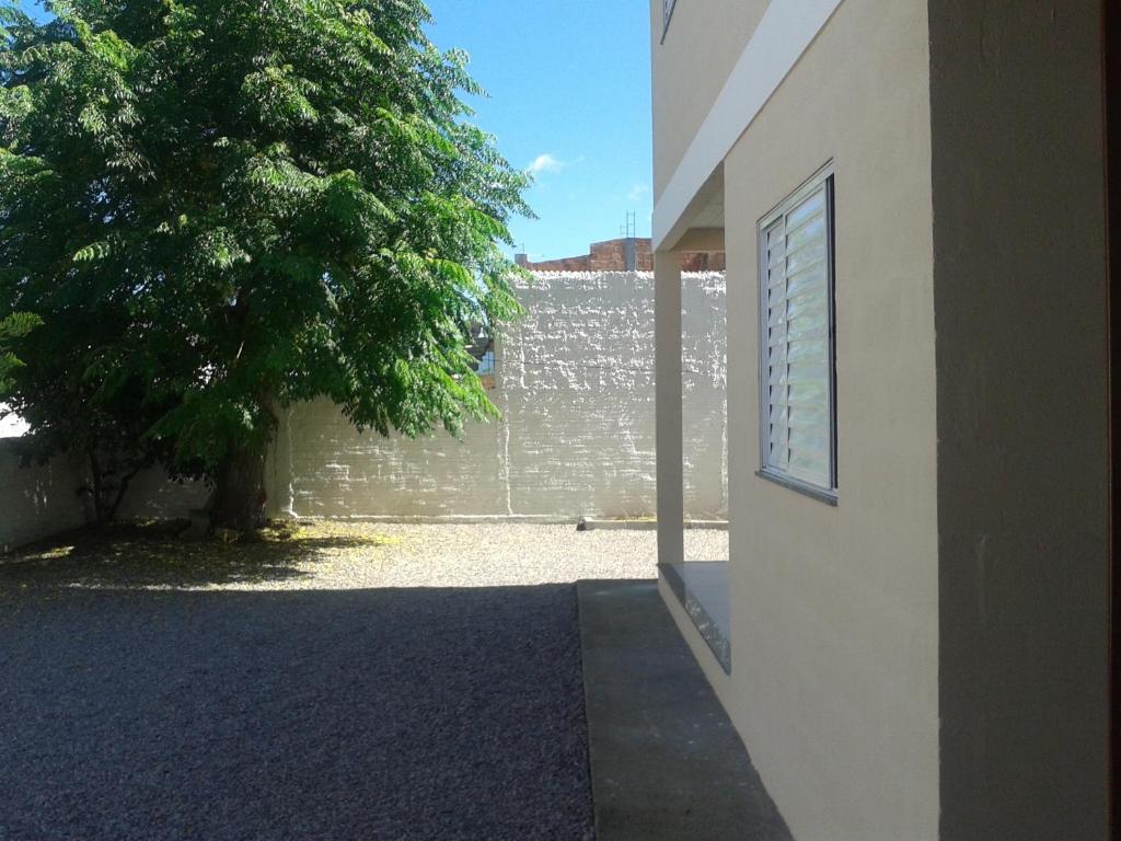 a building with a tree next to a wall at Casa de Temporada Farias in Palhoça