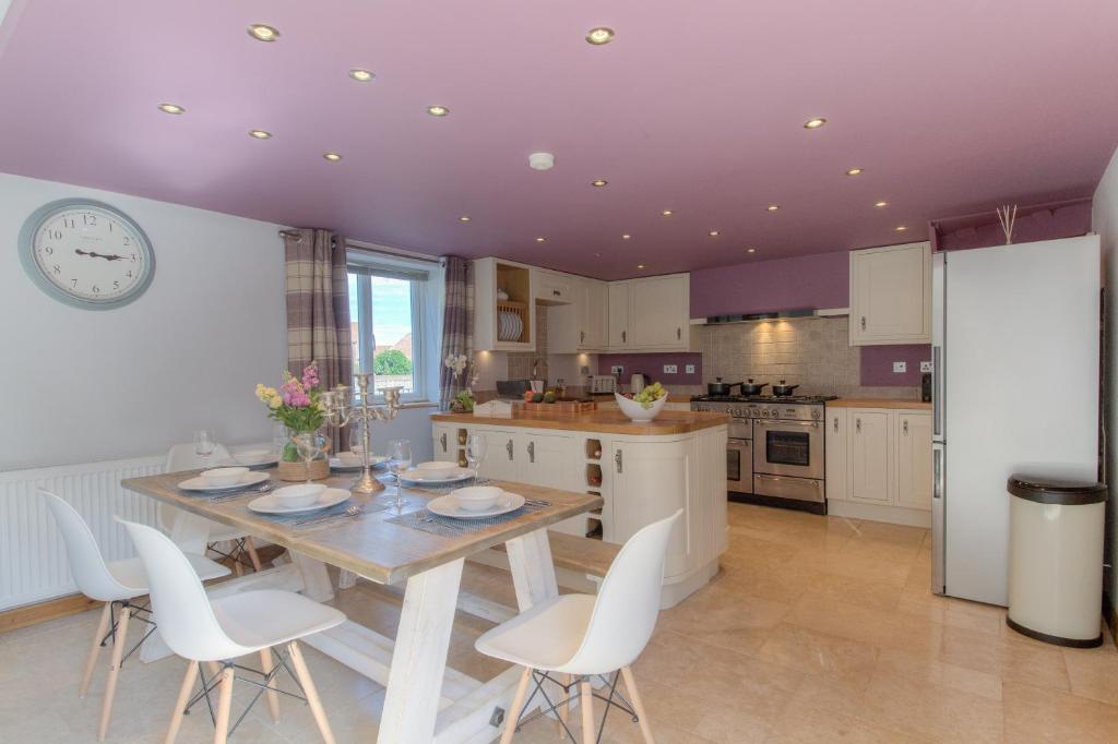 a kitchen with a wooden table and white chairs at Beach Breeze Cottage - 3 Bed in Caister-on-Sea