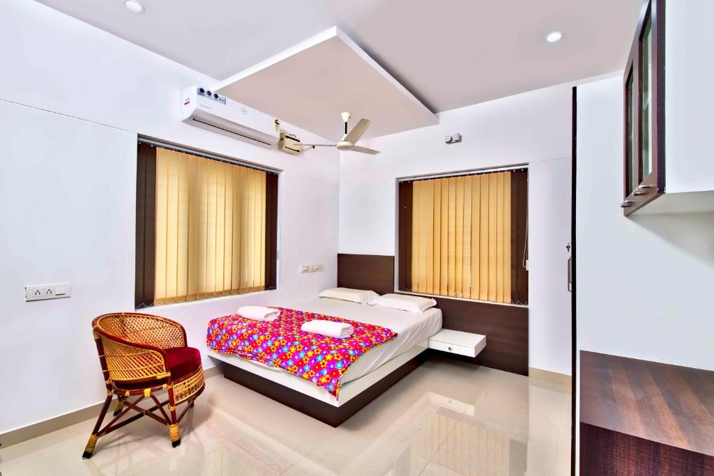 a bedroom with a bed and a chair at Rams Guest House Near Lulu Mall in Trivandrum