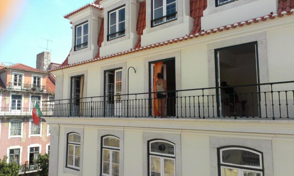 a man standing on the balcony of a white building at Vistas de Lisboa Hostel in Lisbon
