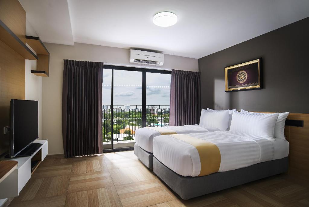 a hotel room with a bed and a large window at Chiva Bangkok Hotel - SHA Plus in Bangkok