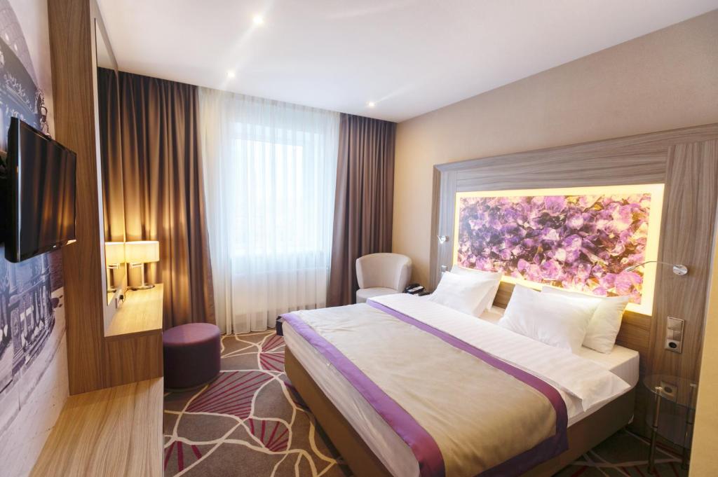 una habitación de hotel con una cama y un cuadro en la pared en Tenet Hotel, en Yekaterinburg