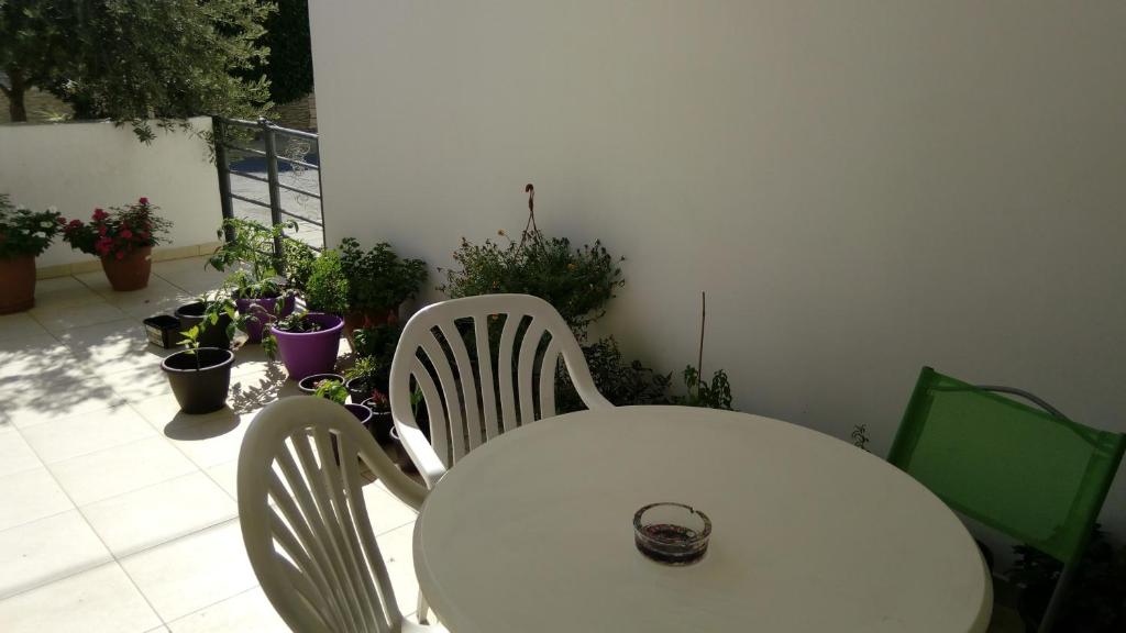 a white table and chairs on a patio with potted plants at Kalampakas Guesthouse in Larnaca
