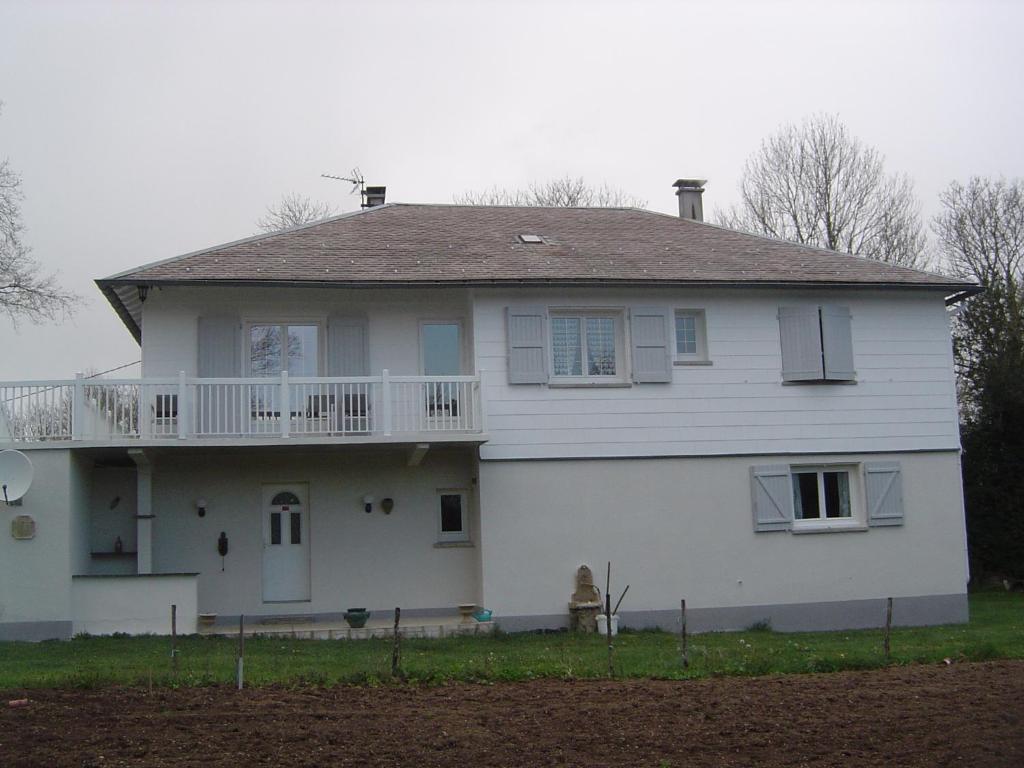 een wit huis met een veranda en een balkon bij CHAMBRE D'HOTES LES MENHIRS in Moulin-Mage