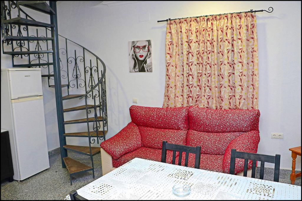 ein Wohnzimmer mit einem roten Sofa und einer Treppe in der Unterkunft Apartamento Plaza España in Conil de la Frontera