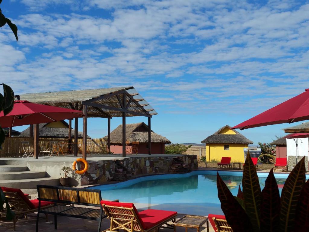 einen Pool in einem Resort mit Stühlen und Sonnenschirmen in der Unterkunft HOTEL H1 ISALO in Ranohira