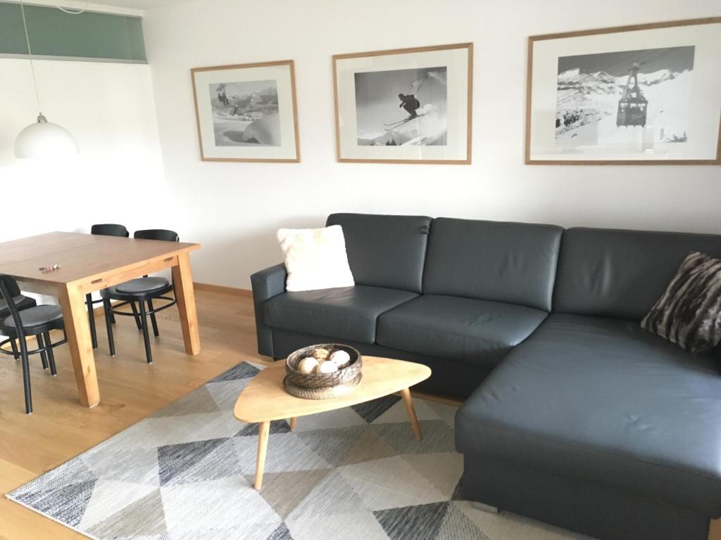 salon z czarną kanapą i stołem w obiekcie Alpen-Fewo, Residenza Quadra 322 w mieście Flims