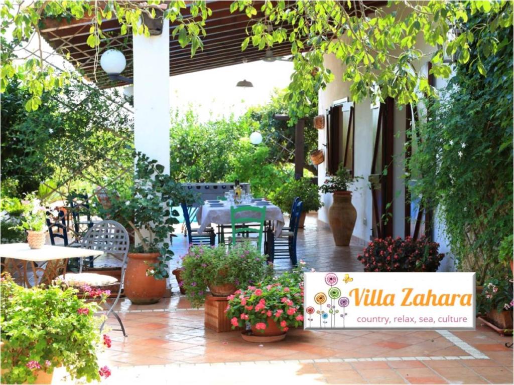 un patio con mesa, sillas y plantas en Villa Zahara, en Ribera
