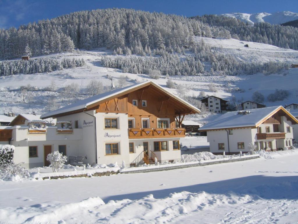 a house in the snow with a mountain in the background at Apart Alpenjuwel in Nauders