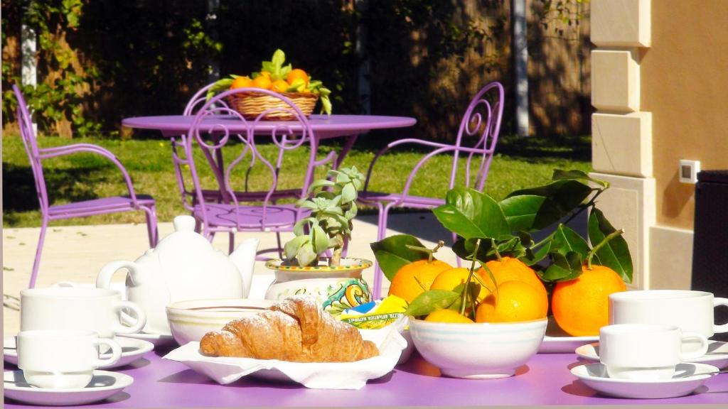 a purple table topped with cups and bowls of fruit at Hotel La Corte Del Sole in Noto