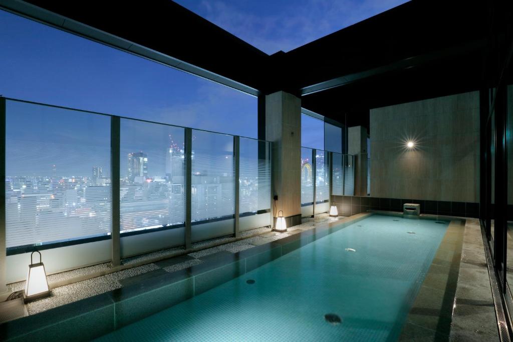 a swimming pool in a building with a view of the city at Candeo Hotels Osaka Namba in Osaka