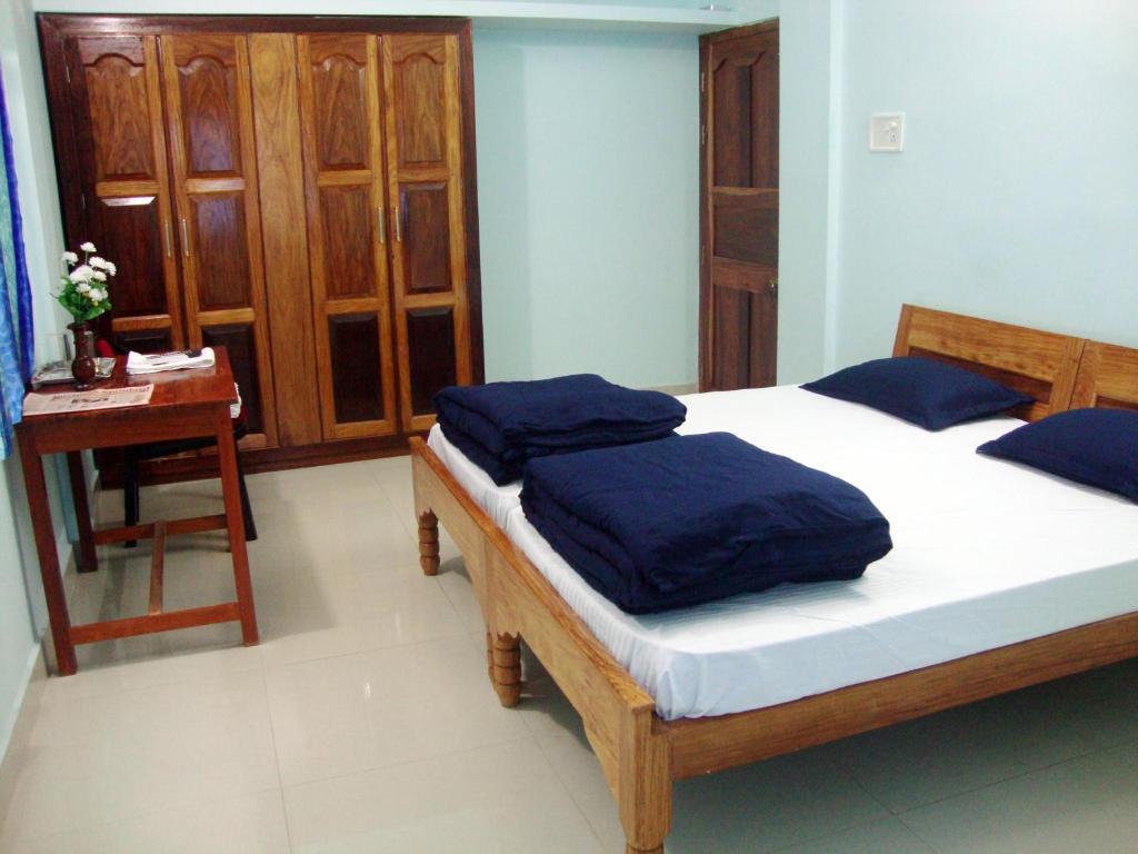 Un dormitorio con una cama con sábanas azules y una mesa. en The Port Vista en Port Blair