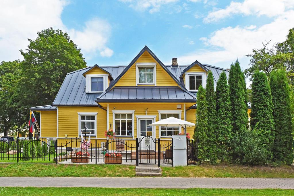 una casa amarilla con techo de metal en Manto Apartamentai, en Druskininkai