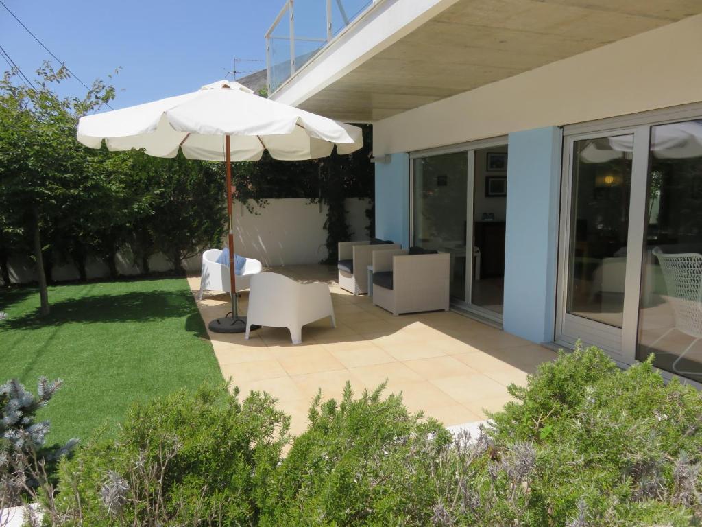 un patio con sombrilla y sillas blancas en Casa azul en Charneca
