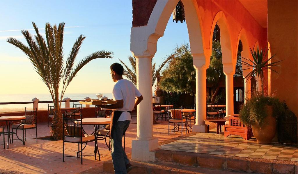 a man standing under an archway at a restaurant at Hotel De Charme Les 3 Chameaux 4 étoiles in Mirleft