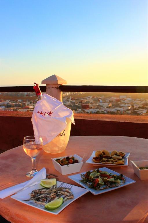 a table with two plates of food and a glass of wine at Hotel De Charme Les 3 Chameaux 4 étoiles in Mirleft
