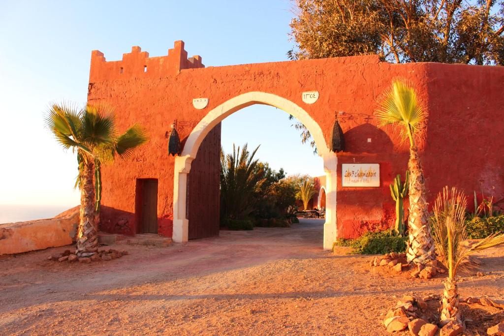 an orange building with an arch in the desert at Hotel De Charme Les 3 Chameaux 4 étoiles in Mirleft