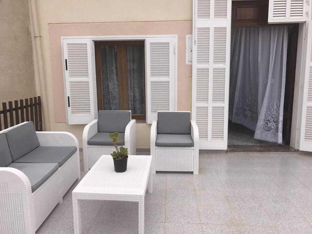 um pátio com cadeiras brancas e uma mesa em Cas Padrins em Can Picafort