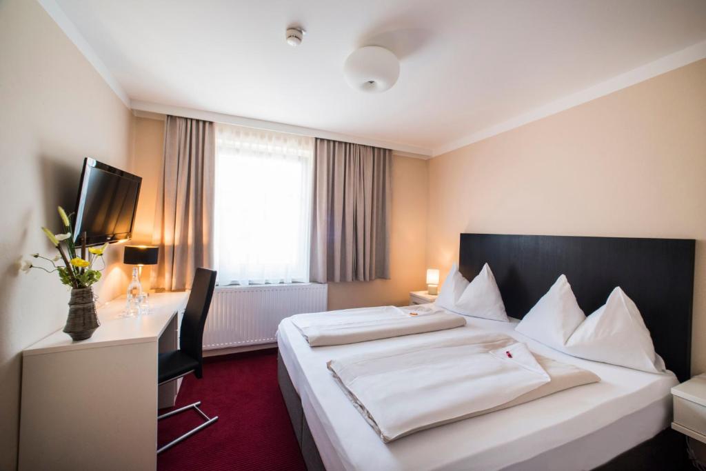 a hotel room with a large bed and a desk at Stadthotel Kramer in Villach