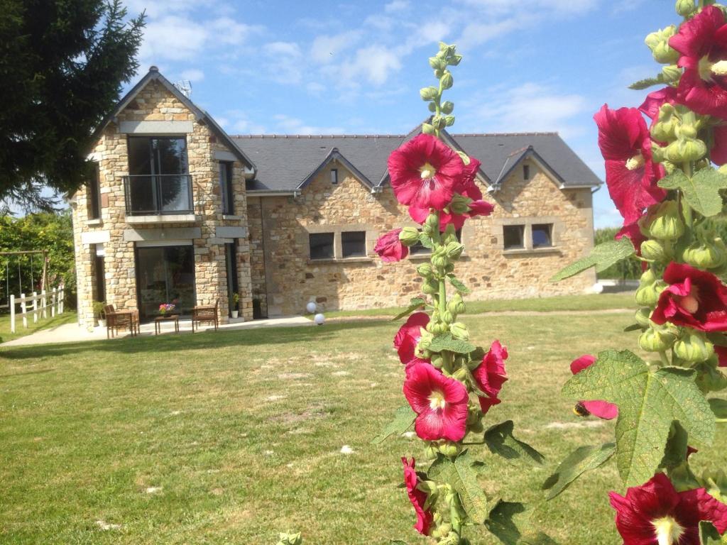 una casa de piedra con flores rojas delante de ella en La Greve Saint Michel, en Beauvoir