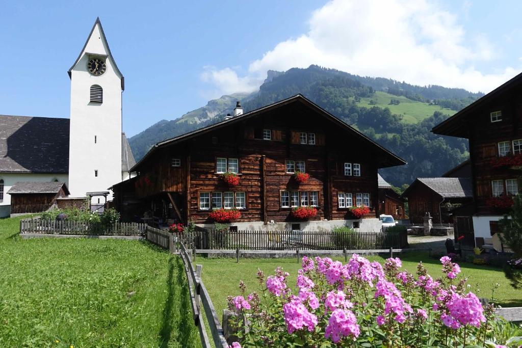 a wooden building with flowers in front of a church at Apartment Sandgasse in Elm