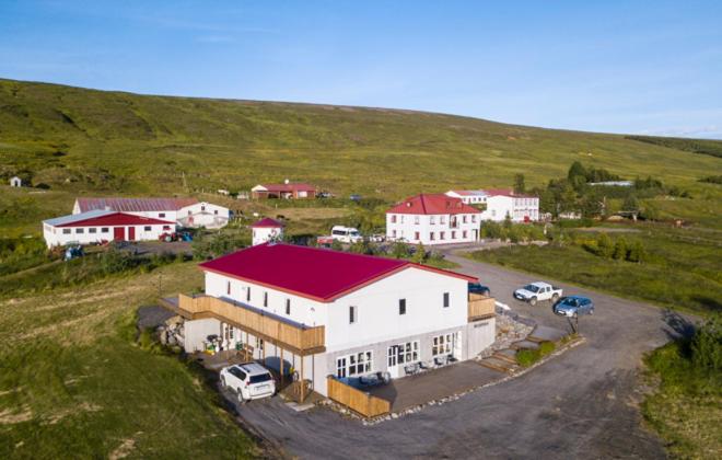 a large white building with a red roof on a hill at Guesthouse Storu-Laugar in Laugar