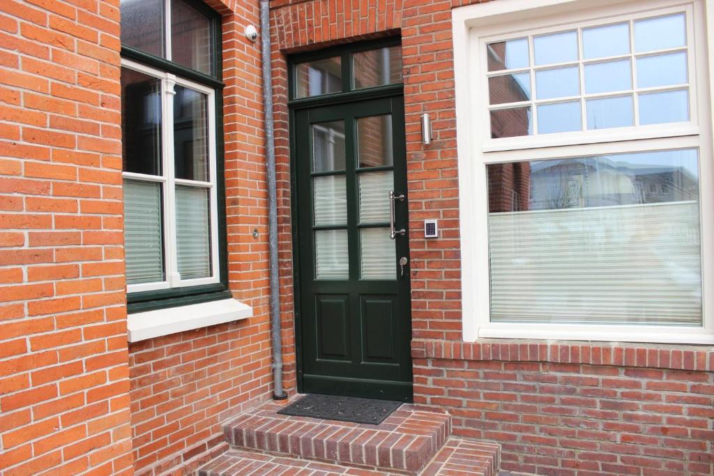 eine grüne Tür an der Seite eines Backsteingebäudes in der Unterkunft Altstadt Wohnung 2 "Hooge" in Borkum