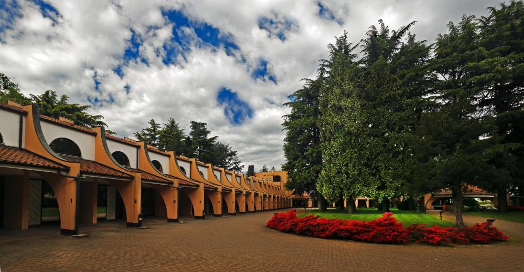 ブスト・アルシーツィオにあるHotel Pinetaの公園内の赤い花の並ぶ建物