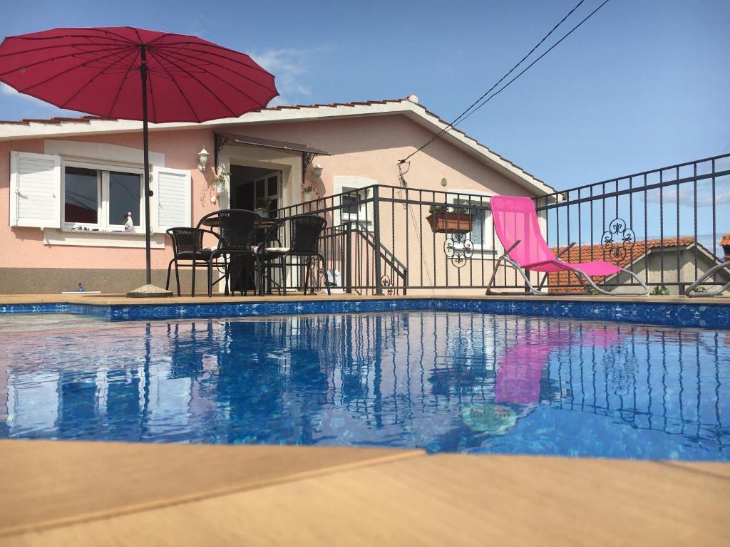 a swimming pool with an umbrella and chairs and a house at House Anastazia Pool & Panoramic Sea View in Lovran
