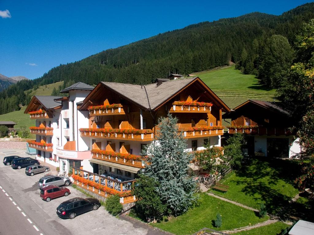 un gran edificio con coches estacionados en un estacionamiento en Hotel Feldrand en Riobianco