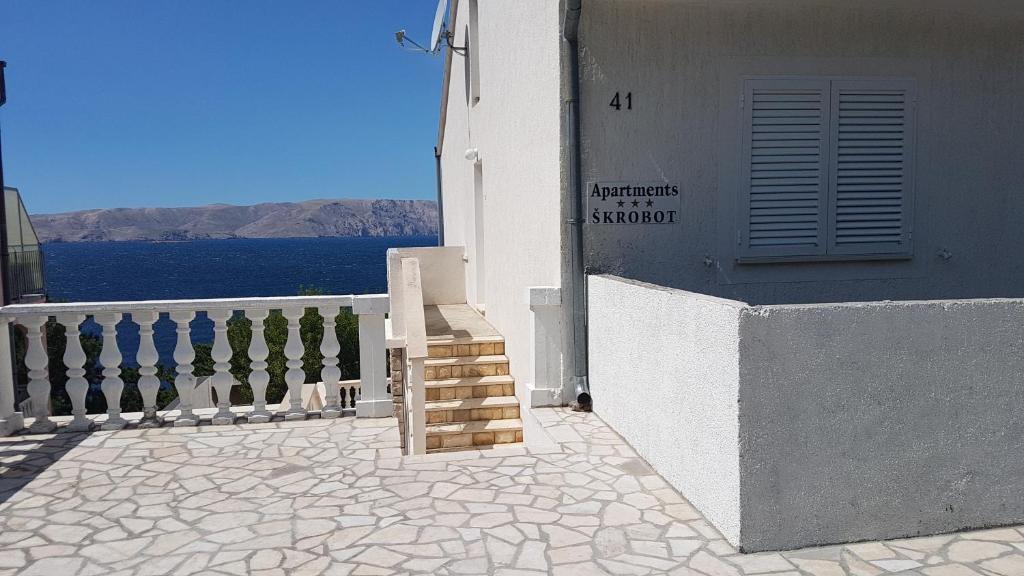 a white building with a staircase next to a door at Apartments Škrobot in Senj