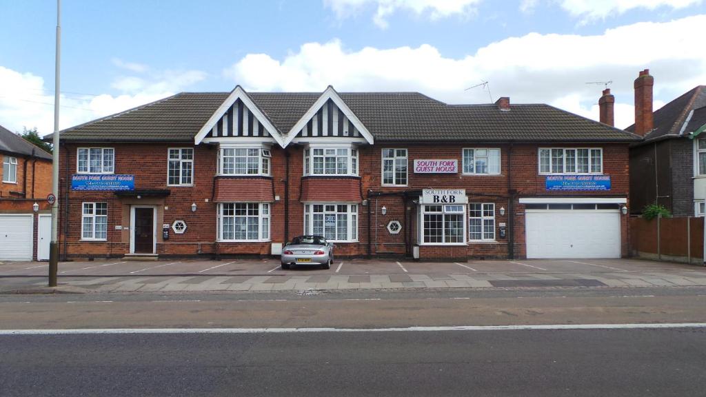 a brick house with a car parked in front of it at South Fork Guest House in Leicester