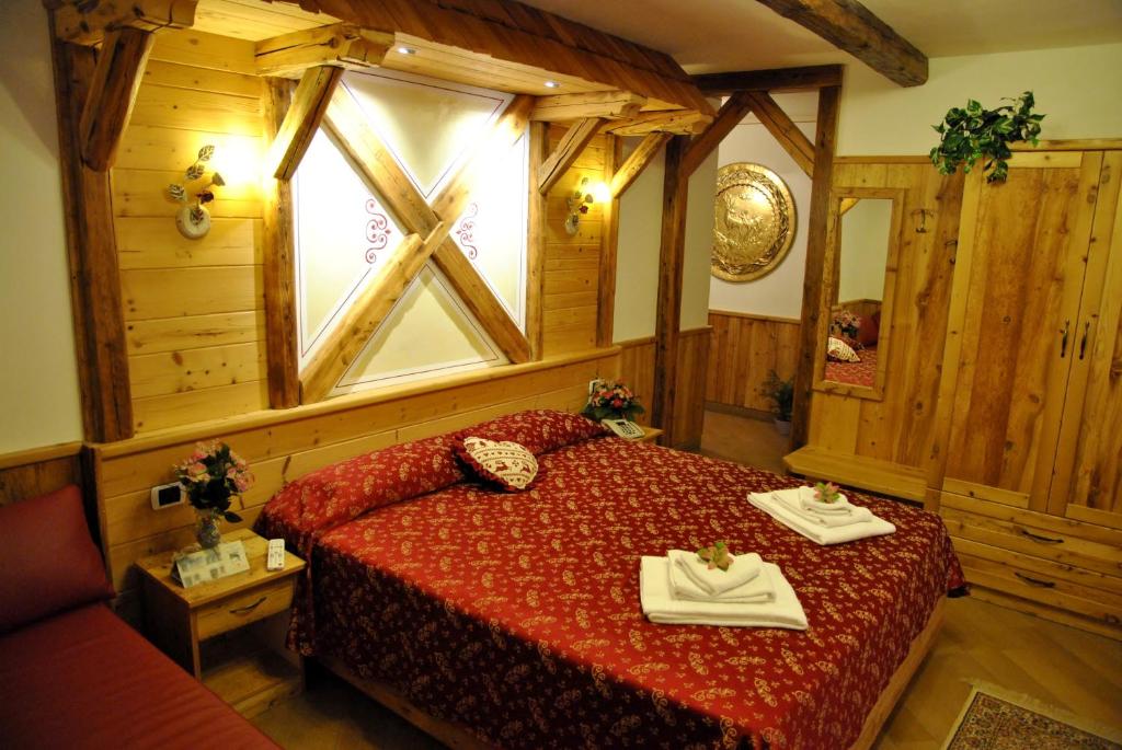 una camera da letto con un letto con copriletto rosso e una finestra di Hotel San Lorenzo a San Lorenzo in Banale