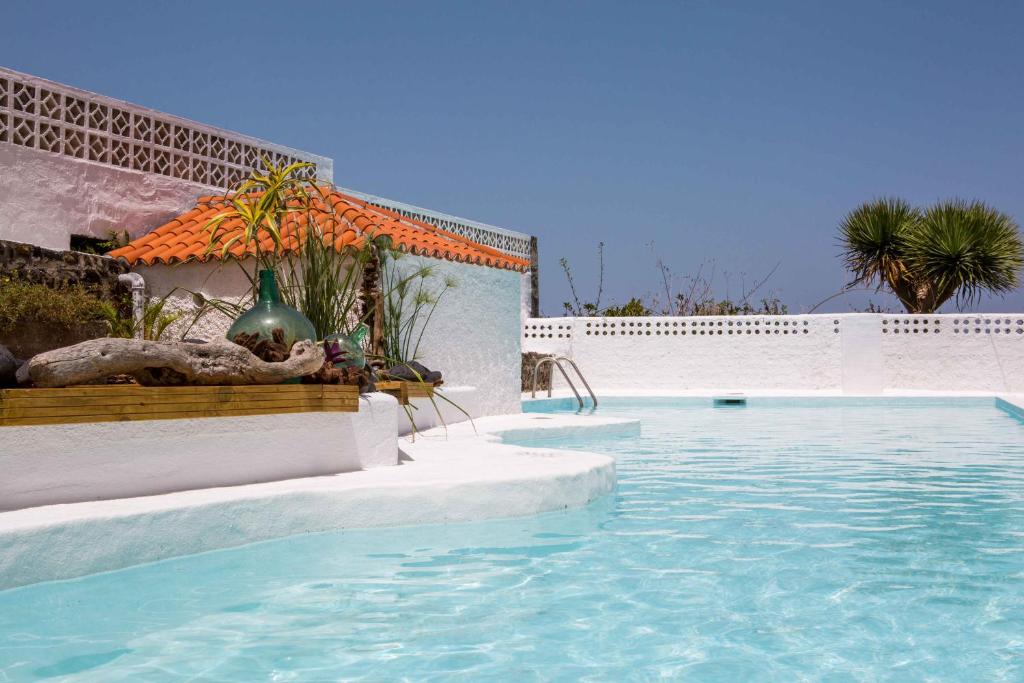 uma piscina com água azul em frente a um edifício em Casa Hedera em Breña Baja