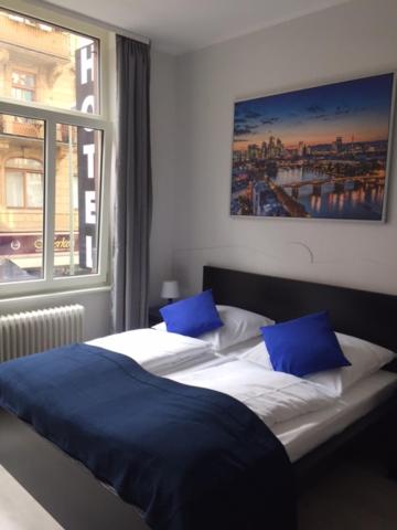 a bedroom with two beds with blue pillows and a window at Main Hotel Frankfurt City in Frankfurt
