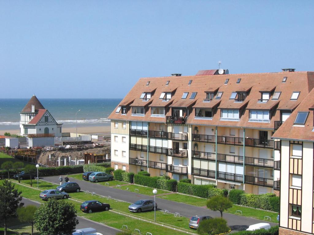 an apartment building next to a street and the ocean at Lagrange Vacances Les Résidences in Villers-sur-Mer
