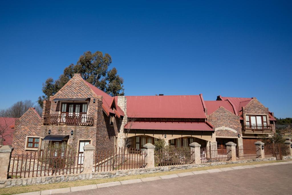 an old brick house with a fence at Windsor House in Dullstroom