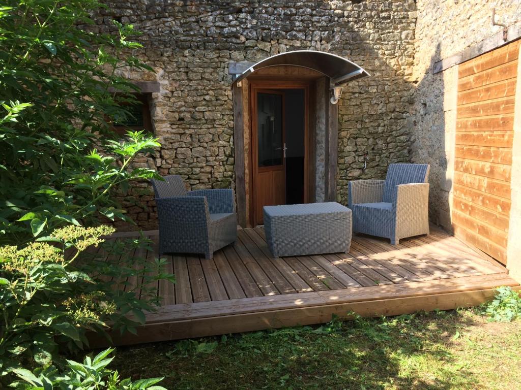 a wooden deck with three chairs and a door at Petite escale Vivonnoise a 2 in Vivonne