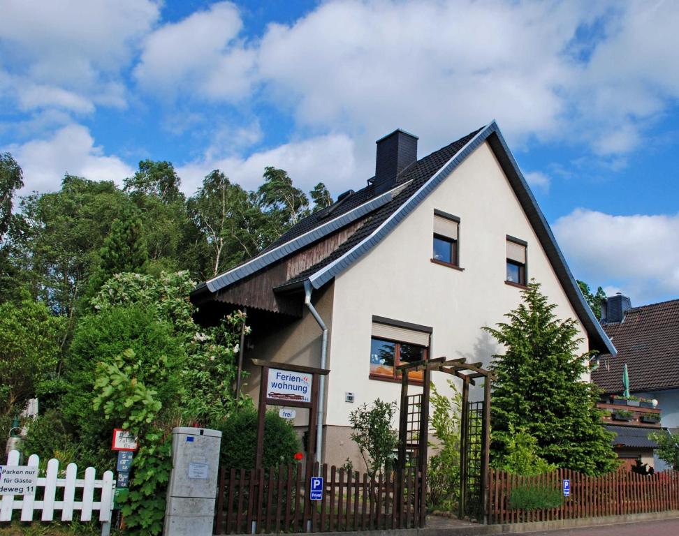 una casa blanca con techo negro y valla en Ferienwohnungen an der Baaber Heide, en Baabe