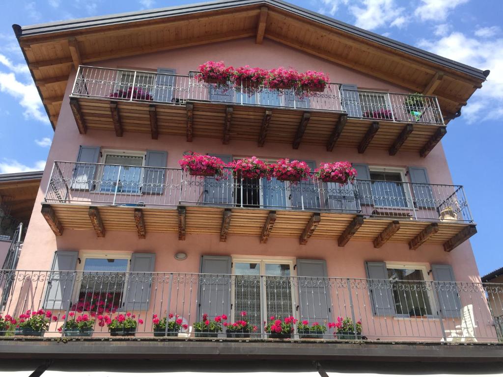 a pink building with flower boxes on balconies at CA' del GIACOMINO in Baselga di Pinè
