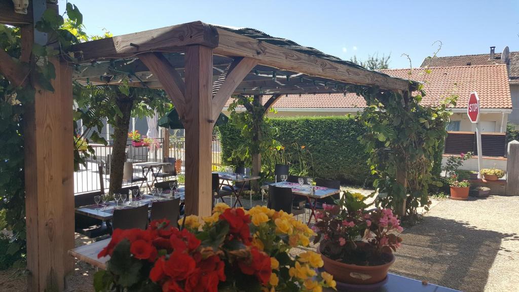 a wooden pergola with tables and flowers in a yard at Logis Cruzel in Maurs