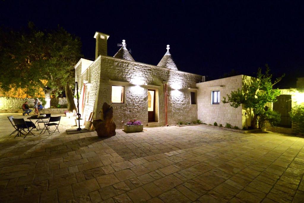 a stone house with a patio at night at Trulli Petra Chiara in Locorotondo