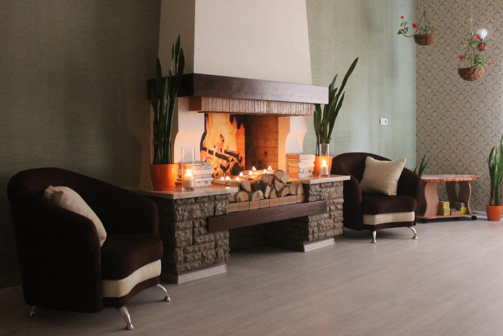 a living room with a fireplace and two chairs at Atlas Hotel in Tomsk