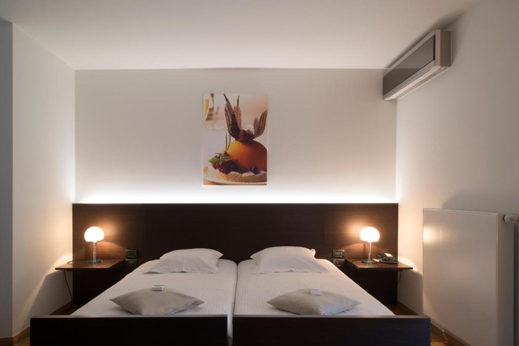 a bedroom with a large white bed with two lamps at Hotel Verlooy in Geel