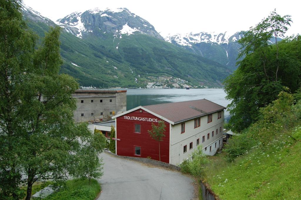 a red building on the side of a road next to a mountain at Trolltunga Studios in Odda