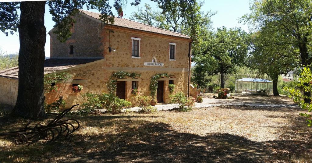 une ancienne maison en pierre au milieu d'une cour dans l'établissement Agriturismo Torrenieri da Alessandro, à Pienza