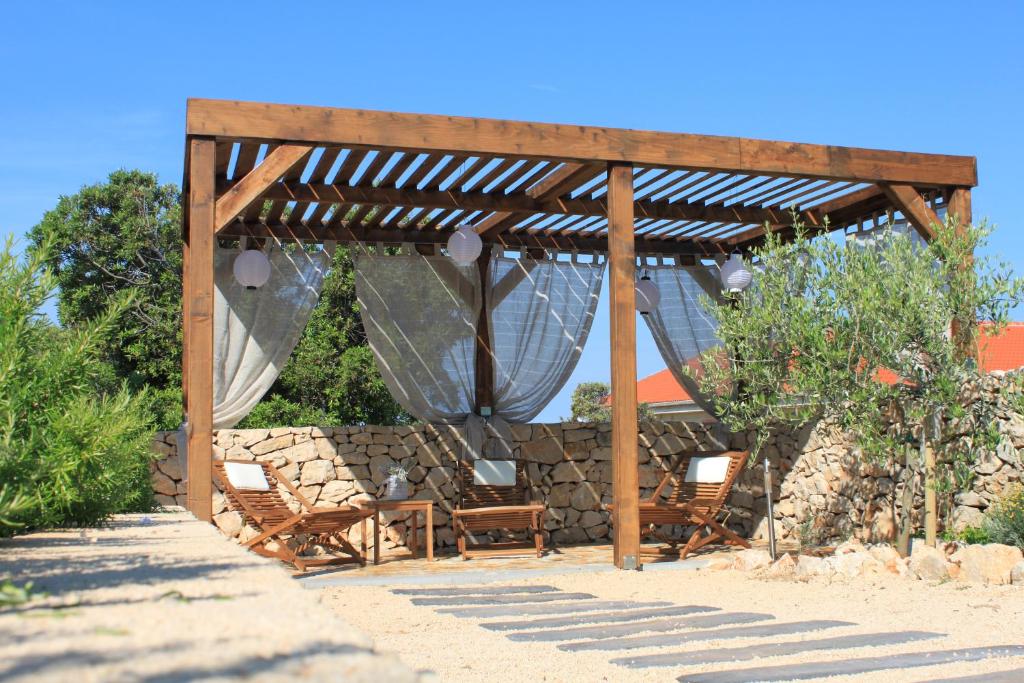 a wooden gazebo with chairs and a stone wall at Apartments Karla i Ivano in Mandre