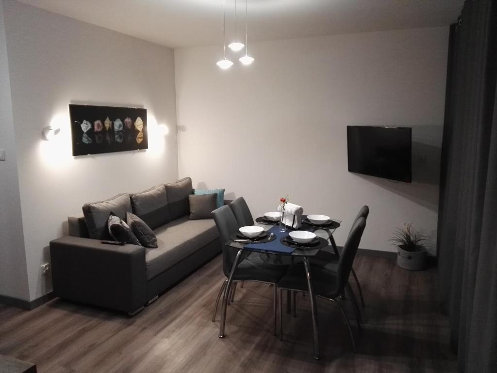 un salon avec un canapé et une table avec des chaises dans l'établissement Apartament Nadmorski - Kompleks Pięć Mórz z basenem, à Sianożęty