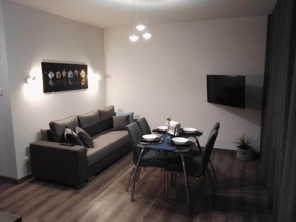 a living room with a couch and a table with chairs at Apartament Nadmorski - Kompleks Pięć Mórz z basenem in Sianozety